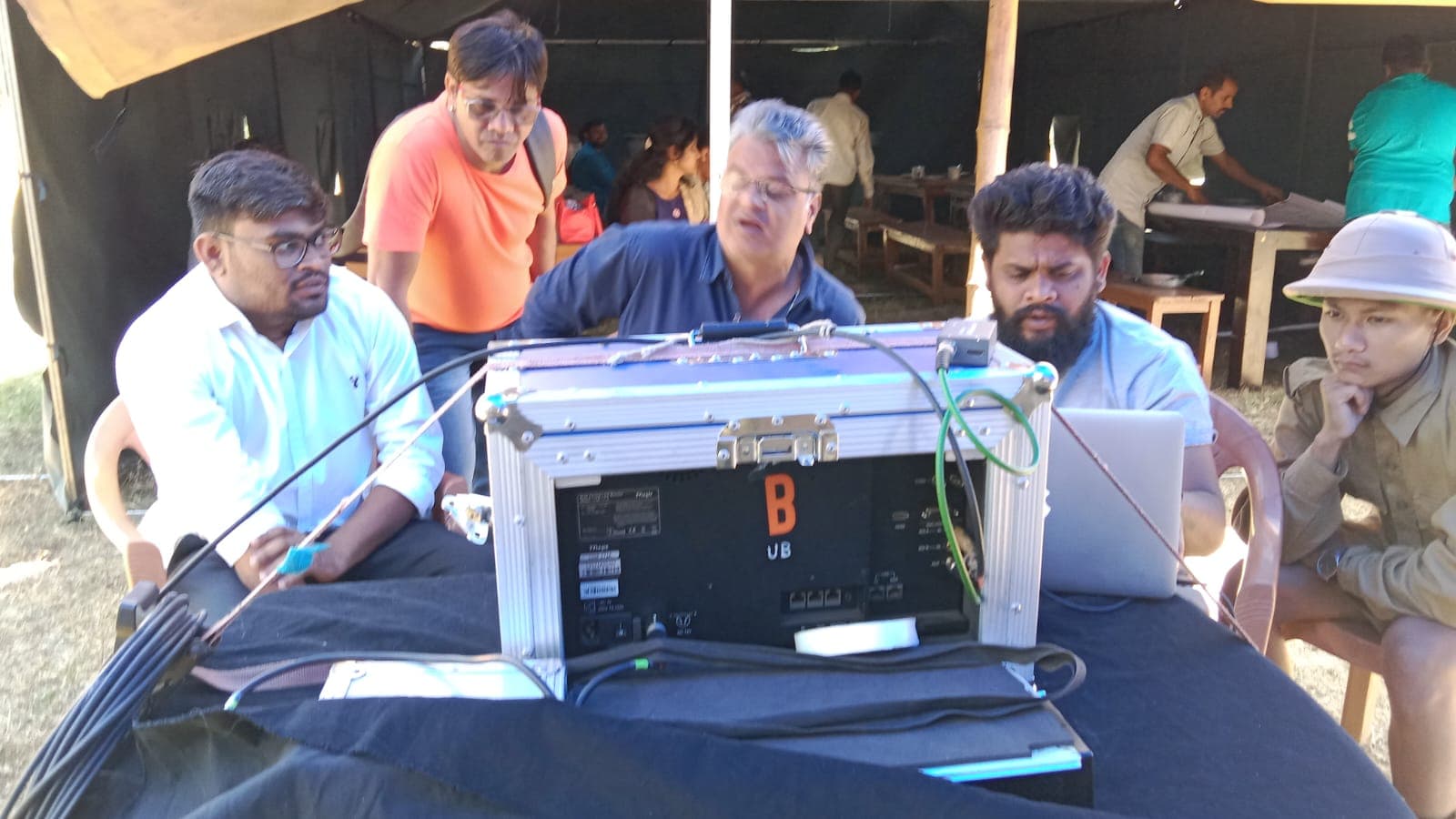Crew gathered around a monitor at the video village on an outdoor set